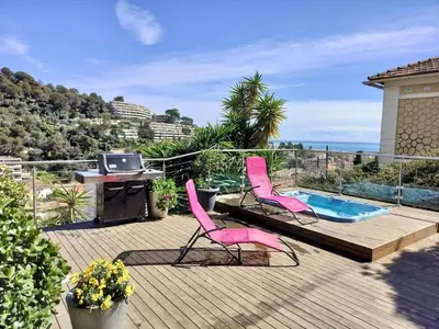 a deck with two pink chairs and a swimming pool at Appartement terrasse jacuzzi in Nice