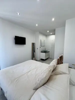 a bedroom with a white bed and a tv on the wall at Charmant 2pcs - 5min des plages in Cagnes-sur-Mer