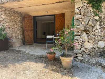 a stone house with a chair and flowers in front of it at Le petit Baou in Saint-Jeannet