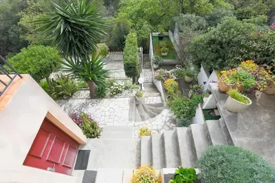 a garden with potted plants and a red door at Villa Bleu Azur - Élégance Privée avec Vue Mer & Montagne in Cagnes-sur-Mer