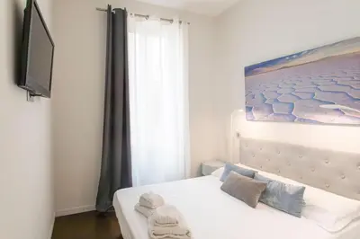 a bedroom with a white bed with a painting on the wall at #60 Grimaldi 2BDR central near beach,promenade AC&WIFI in Nice