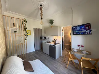 a room with a bed and a kitchen with a table at Studio de Charme à Nice - Idéal télétravail - Balcon - Plage à 300m in Nice