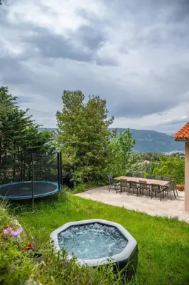 a hot tub in the grass next to a table at La Quiétude - Spacious - Magnificent mountain view - AC - Jacuzzi in Aspremont