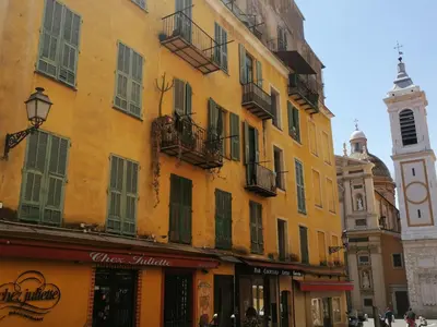 a yellow building with windows and a clock tower at Bohemian style and luminous balcony in Nice