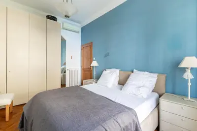a bedroom with a large bed with a blue wall at HappyFew suite Palazzo in Nice