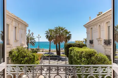 a balcony with a view of the ocean and palm trees at HappyFew suite Palazzo in Nice