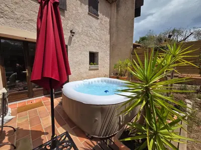 a hot tub on a patio with a red umbrella at A la campagne aux portes de Nice in Falicon