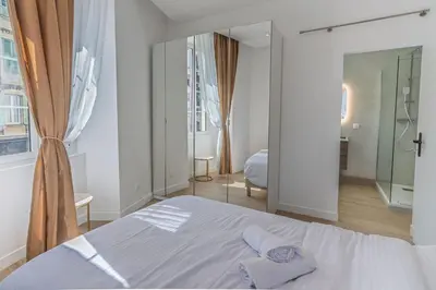a white bedroom with a bed and a mirror at Magnifique appartement - Jacuzzi - Port de Nice in Nice