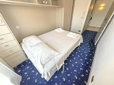 a small room with a bed and blue carpet at Panoramic Pebbles Azur in Nice