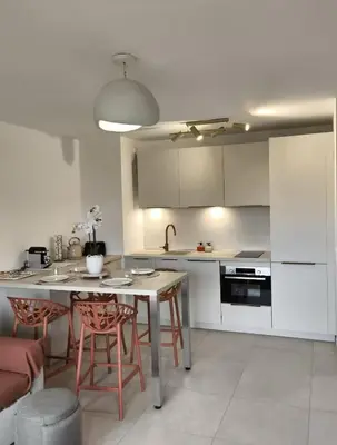 a kitchen with a table and chairs in a room at Piscine Rooftop Résidence Neuve in Saint-Laurent-du-Var