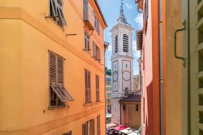 an alley between two buildings with a clock tower at NEW Appartement vieux Nice à côté de la plage AC in Nice