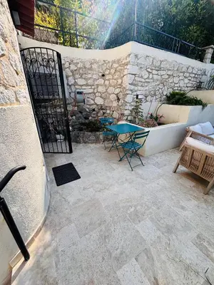 a patio with a table and chairs and a stone wall at Appartement 1 chambre - grande terrasse in Nice