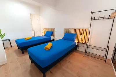 two beds in a room with blue sheets and yellow pillows at Grand appartement idéal famille, proche plage, bon emplacement pour visiter la Côte d'Azur in Nice