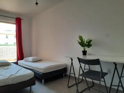 a room with two beds and a desk with a plant at Appartement 3 chambres spacieux prés des plages à Nice in Nice