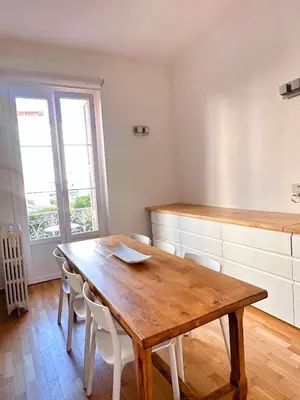 a kitchen with a wooden table and white cabinets at L'appart in Nice