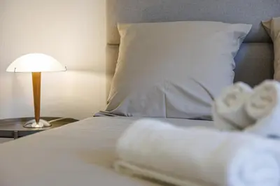 a white bed with a white pillow and a lamp at FEEL HOME - CAIS De PIERLAS in Nice