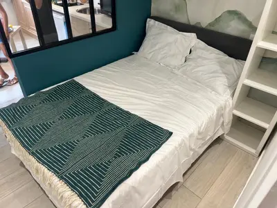 a bed with white sheets and a green and white blanket at Studio du Domaine du Piol in Nice
