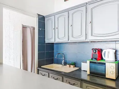 a kitchen with white cabinets and a red appliance at Studio Le Savoy Promenade des Anglais-5 by Interhome in Nice
