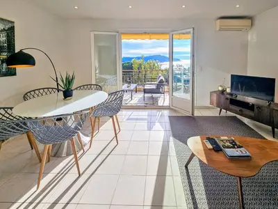 a living room with a table and chairs at Beau 2 pieces avec vue imprenable sur la rade in Villefranche-sur-Mer