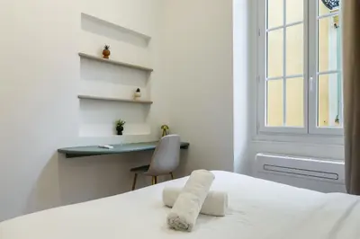 a white bedroom with a bed and a desk at Charme et modernite au coeur du Vieux Nice in Nice