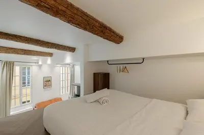 a white bedroom with a large bed and a window at Charme et modernite au coeur du Vieux Nice in Nice