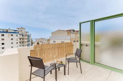 a balcony with two chairs and a table on a roof at COCO BEACH AP4476 by Riviera Holiday Homes in Nice
