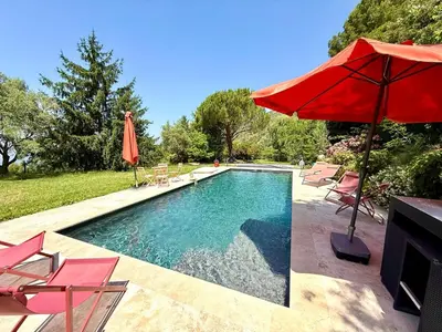 a swimming pool with a red umbrella and chairs at Havre de paix proche de Nice in Aspremont