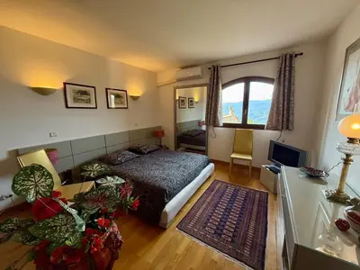 a bedroom with a bed and a desk and a television at Havre de paix proche de Nice in Aspremont