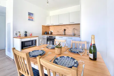 a kitchen with a dining room table with wine glasses at Appartement Fleuri vue mer - Welkeys in Saint-Laurent-du-Var