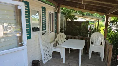 a porch with white chairs and a white table and chairs at Mobil home Oasi in Cagnes-sur-Mer