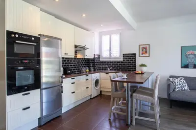 a kitchen with a table and a stainless steel refrigerator at L4 Fayad 2BDR Hotel des Postes Central, Massena AC 2Balconies in Nice