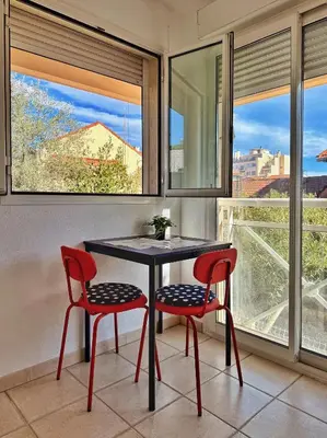 a table and two chairs in a room with windows at Studio près mer et aéroport - Studio near sea and airport in Nice