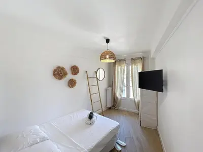 a white living room with a cat sitting on a bed at Beautiful 4 rooms sea airport in Nice