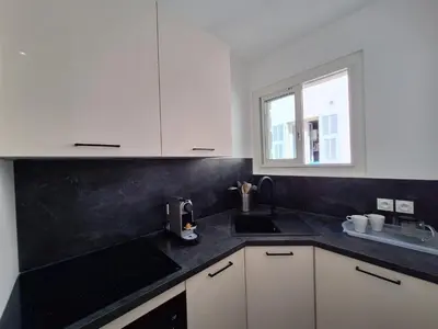 a kitchen with white cabinets and a black counter top at Iconic and bright style in Nice in Nice