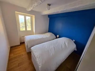 a room with two beds and a blue wall at Plaisirs entre mer et montagne in Aspremont