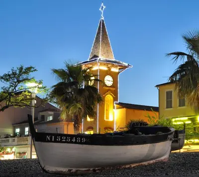 a clock tower with a boat in front of a building at Studio rénové à deux pas de la mer et commerces in Cagnes-sur-Mer