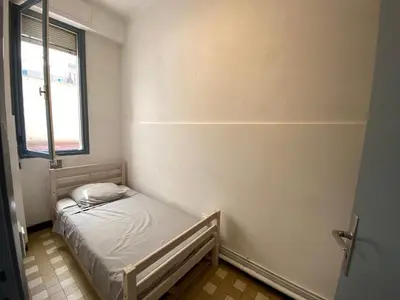 a small bed in a room with a window at Easy and accessible beach flat near the university in Nice