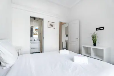a white bedroom with a large white bed with two white towels at Appartement Perle - Welkeys in Nice