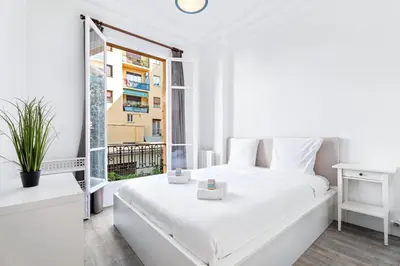a white bedroom with a white bed and a window at Appartement Perle - Welkeys in Nice