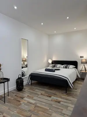 a white bedroom with a bed and a mirror at Charmant studio en centre de Nice in Nice