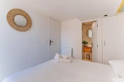 a white bedroom with a white bed and a mirror at AUTHENTIC VILLEFRANCHE AP4472 By Riviera Holiday Homes in Villefranche-sur-Mer