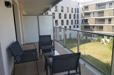 a balcony with chairs and a view of a building at Seafront apartment with pool and comfort in Saint-Laurent-du-Var