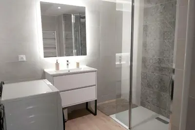 a white bathroom with a sink and a shower at Seafront apartment with pool and comfort in Saint-Laurent-du-Var