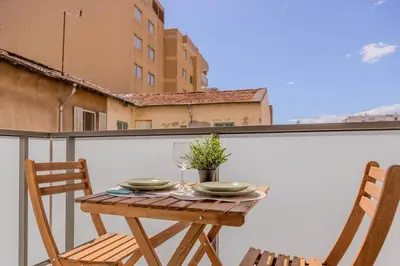 a table and two chairs on a balcony with a table and two glasses at Nice 2 pièces charmant proche port et transports in Nice