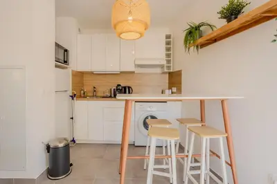 a kitchen with a counter with stools and a washing machine at Nice 2 pièces charmant proche port et transports in Nice
