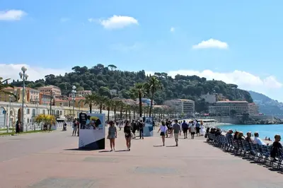 a group of people walking on a sidewalk near the water at Beach and Sun two minutes away in Nice