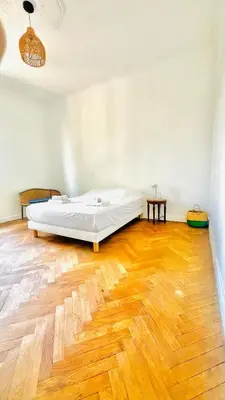 a bed in a room with a wooden floor at Sublime 2 bedroom spacious and bright AC Private parking in Nice