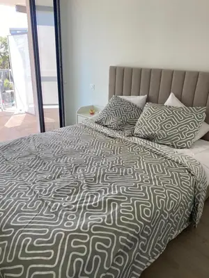 a bed with a black and white comforter and pillows at New flat with swimming pool on rooftop in Saint-Laurent-du-Var