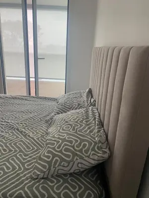 a bed with a pillow sitting next to a window at New flat with swimming pool on rooftop in Saint-Laurent-du-Var