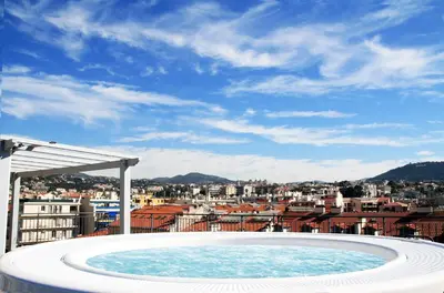 a hot tub with a view of a city at Hôtel & Appartements Monsigny in Nice